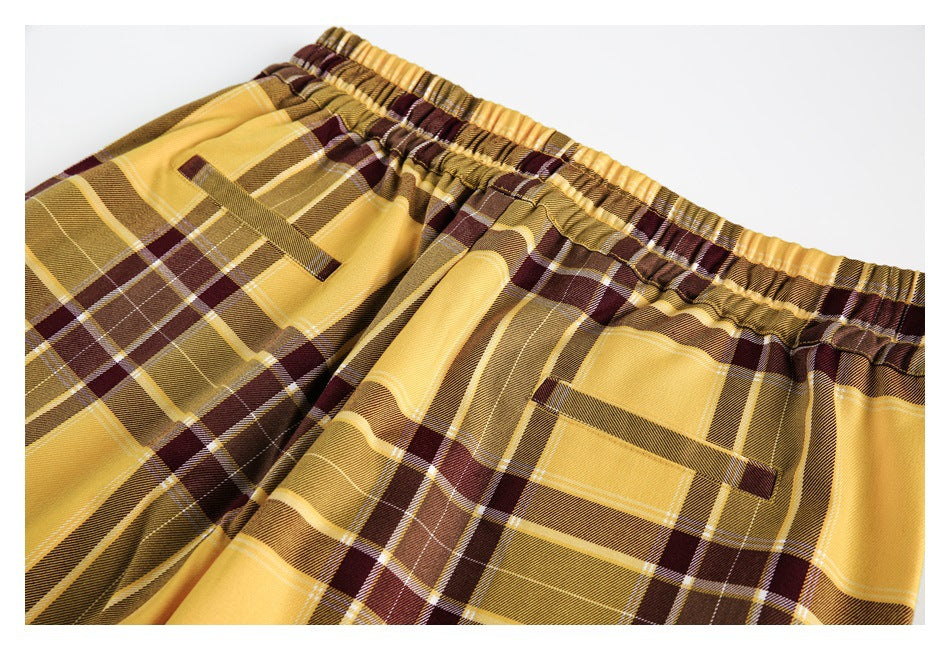 Close-up of plaid trousers showing the gathered elastic waistband and two front pockets.