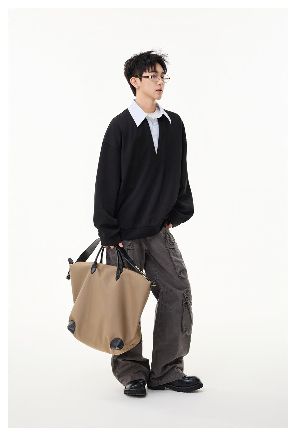 Side view of a model wearing a black oversized V-neck pullover over a white collared shirt.