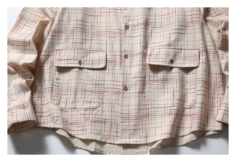 Cropped front view of an off-white plaid button-up shirt with two button-flap chest pockets.