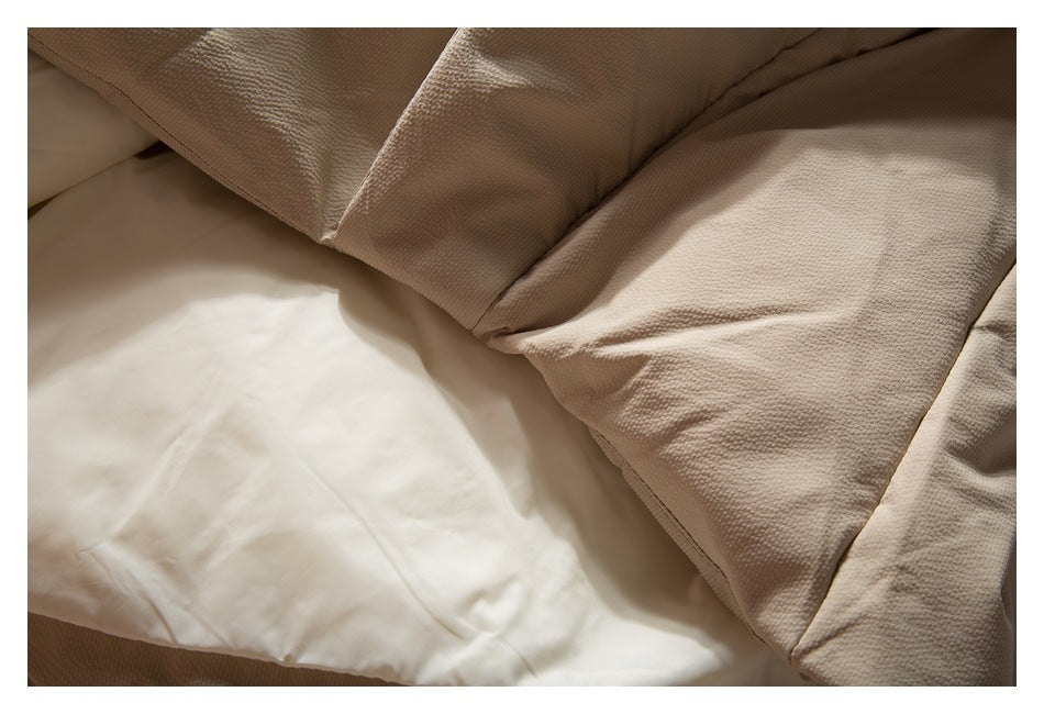 Close-up of beige textured fabric draped over smooth white fabric.