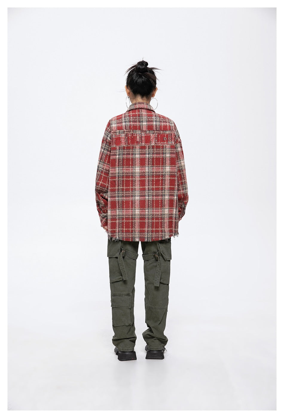 Back view of a model wearing a red tartan shirt jacket with lettering across the upper back.