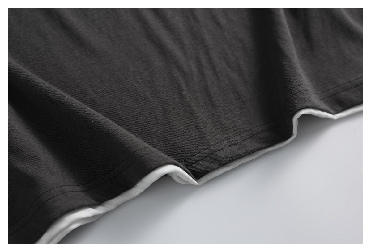 Close-up of the charcoal shirt's stitched lower hem, with white fabric visible beneath.