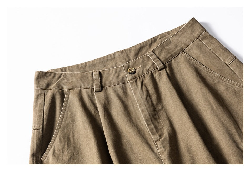 Close-up of khaki-brown cargo shorts showing the waistband, button, belt loops, pleats and front pocket.