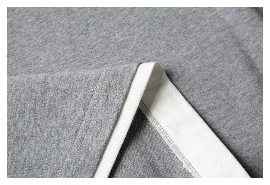 Close-up of a gray shirt seam and white ribbed trim.