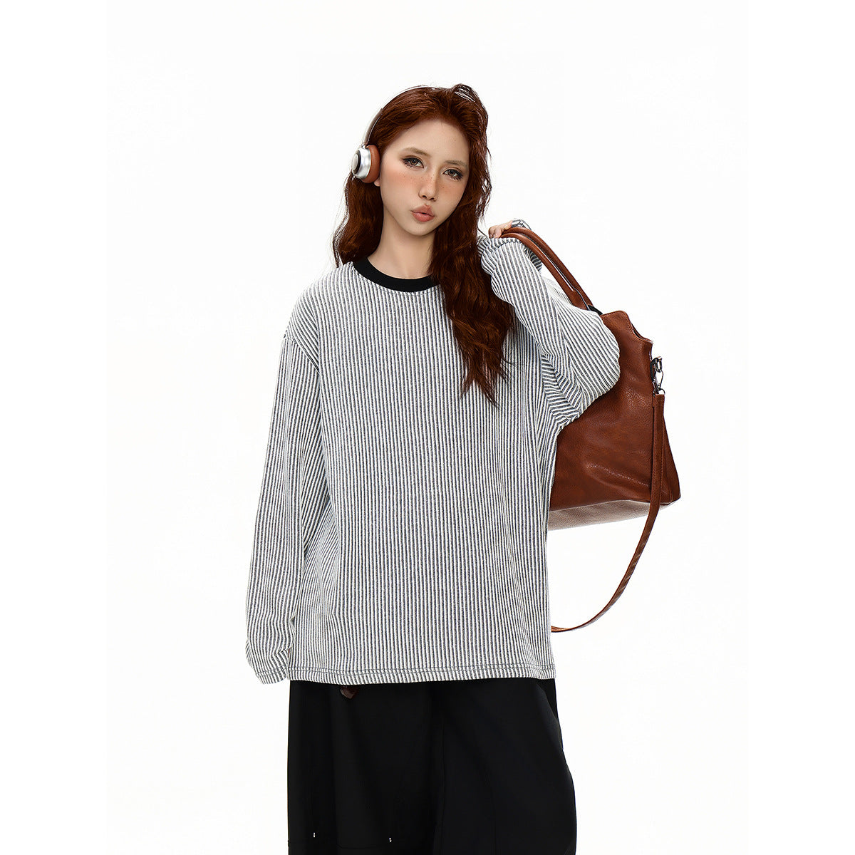 Model wearing an oversized white and gray vertically striped long-sleeve top with a black crew neckline.