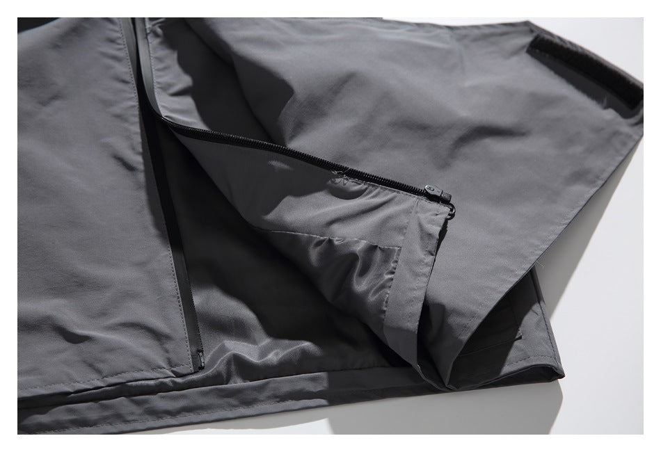 Close-up of a charcoal gray jacket with a partially open zippered pocket and hook-and-loop tab.