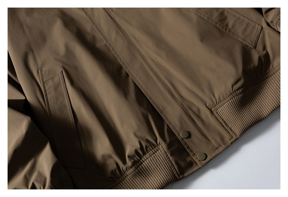 Close-up of the brown jacket front showing a pocket, snap buttons and ribbed hem.