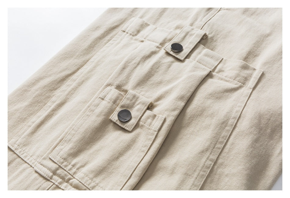 Close-up of a beige cargo-style pants pocket with two dark snap-button tabs.