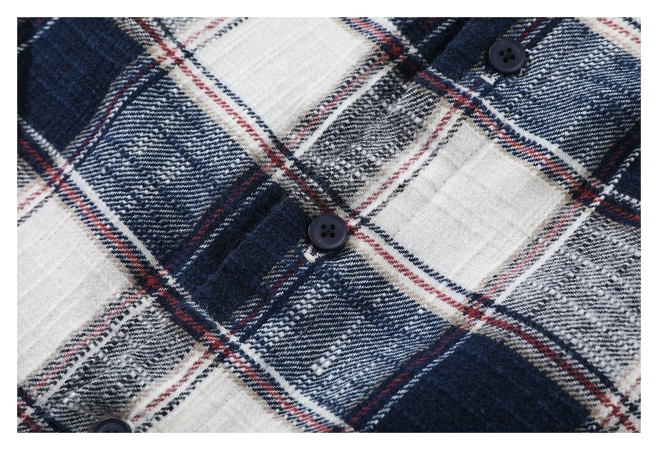 Close-up of dark buttons on a navy, white, gray, and red plaid shirt.