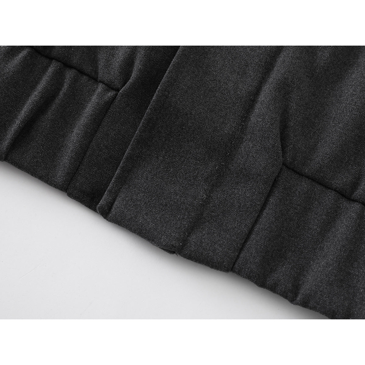 Close-up of a dark charcoal jacket panel with a vertical seam and pocket opening.