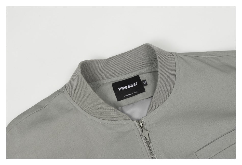Close-up of the gray jacket's ribbed collar, front zipper, chest pocket edge and sewn-in neck label.