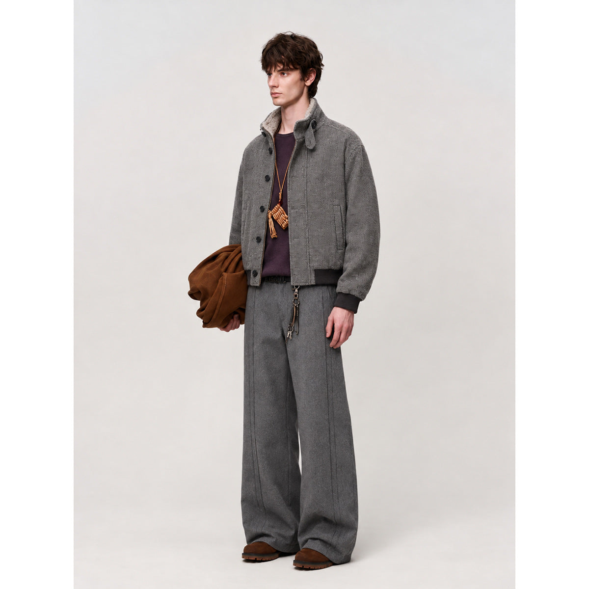 Model wearing a gray button-front jacket and matching wide-leg trousers with brown shoes.
