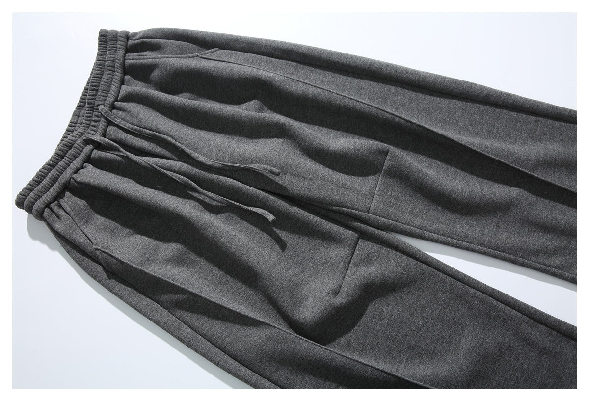 Charcoal drawstring pants laid diagonally, showing the front pockets and straight legs.