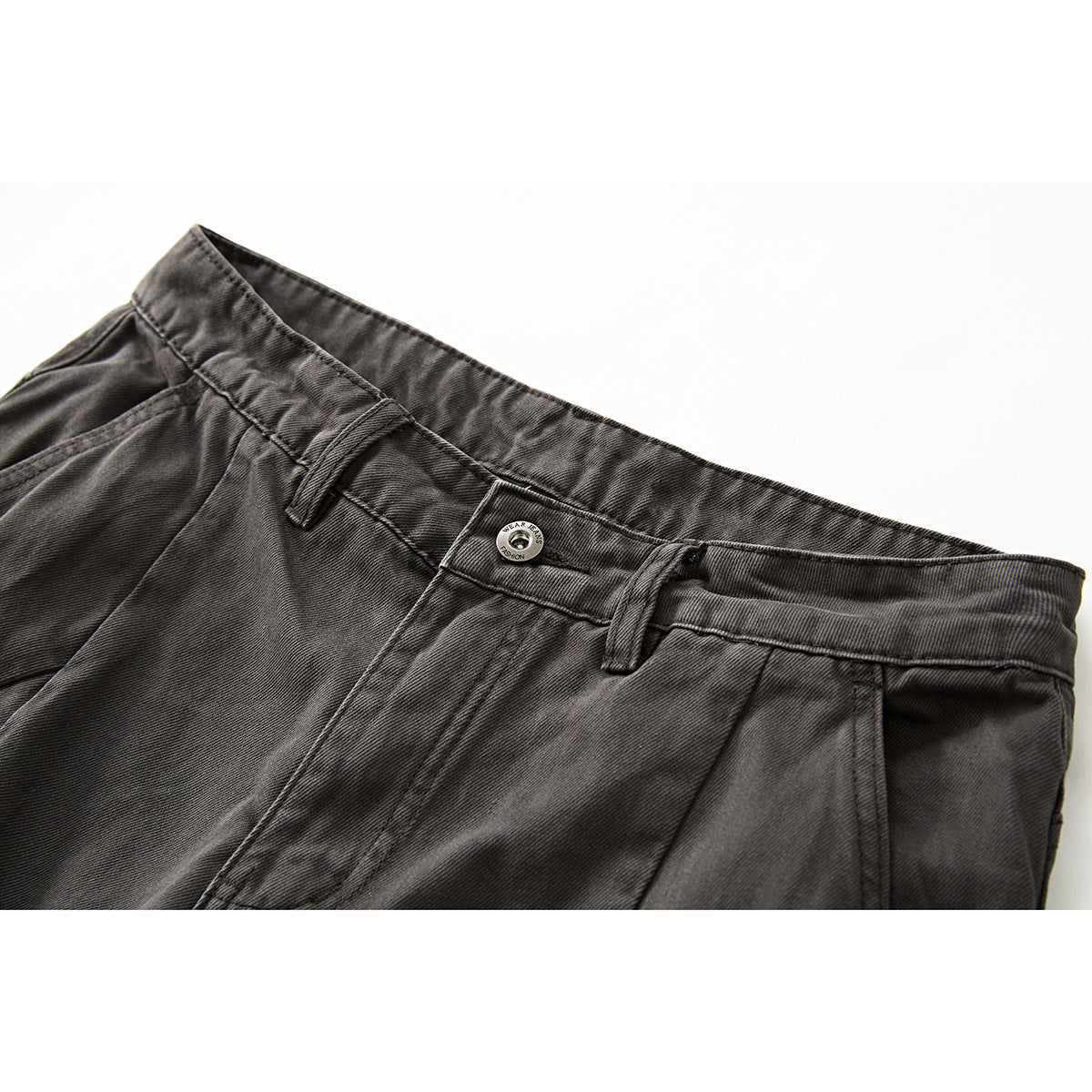 Close-up of charcoal gray shorts showing the waistband, belt loops, button, and front seam.