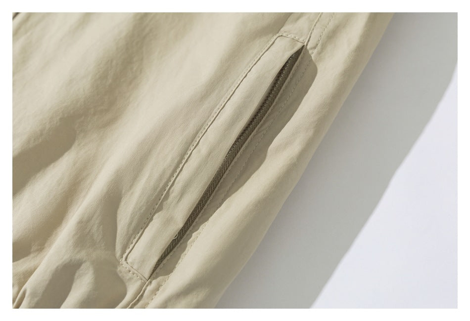 Close-up of a light beige garment showing a narrow zippered pocket with stitched edges.