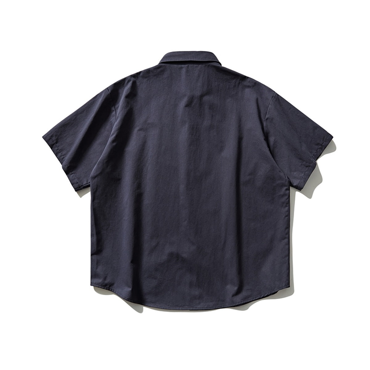 Back view of navy short-sleeve shirt with plain back panel and collar, flat lay