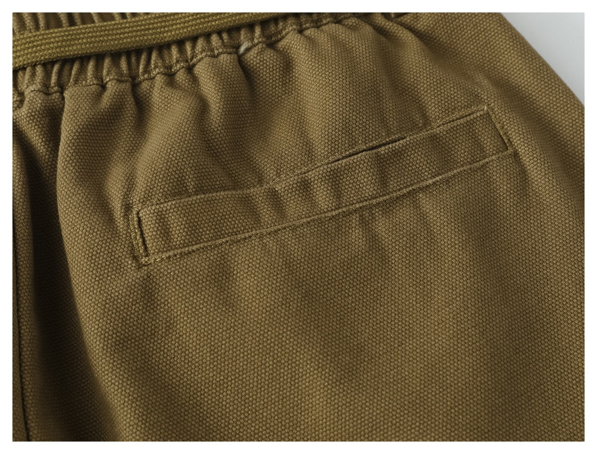 Close-up of an olive-brown trouser back pocket below the gathered elastic waistband.