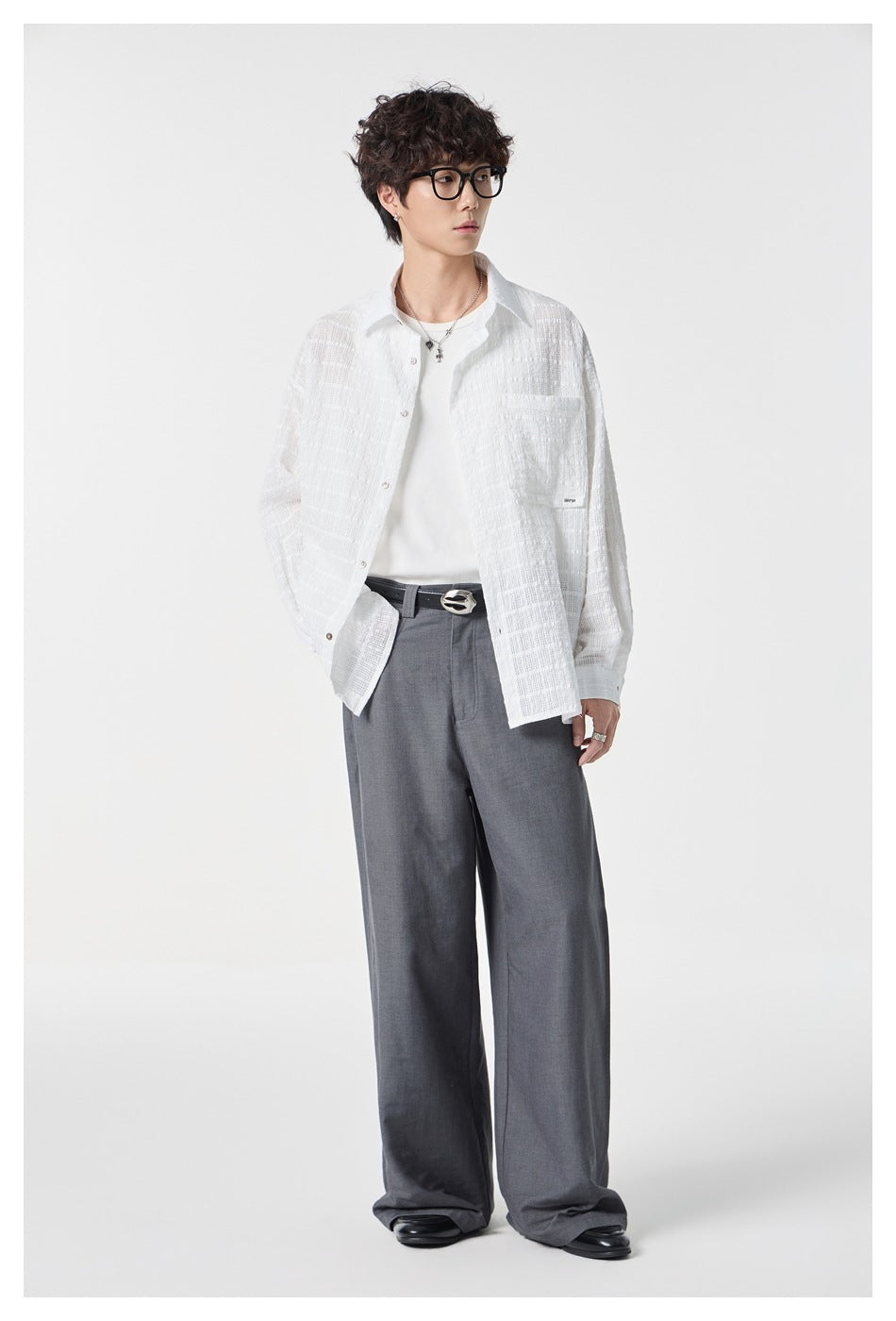 Full-length view of a model wearing a white textured button-up shirt and gray wide-leg trousers.