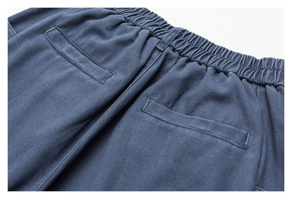 Close-up of blue-gray trousers with an elastic waistband and slanted pockets.