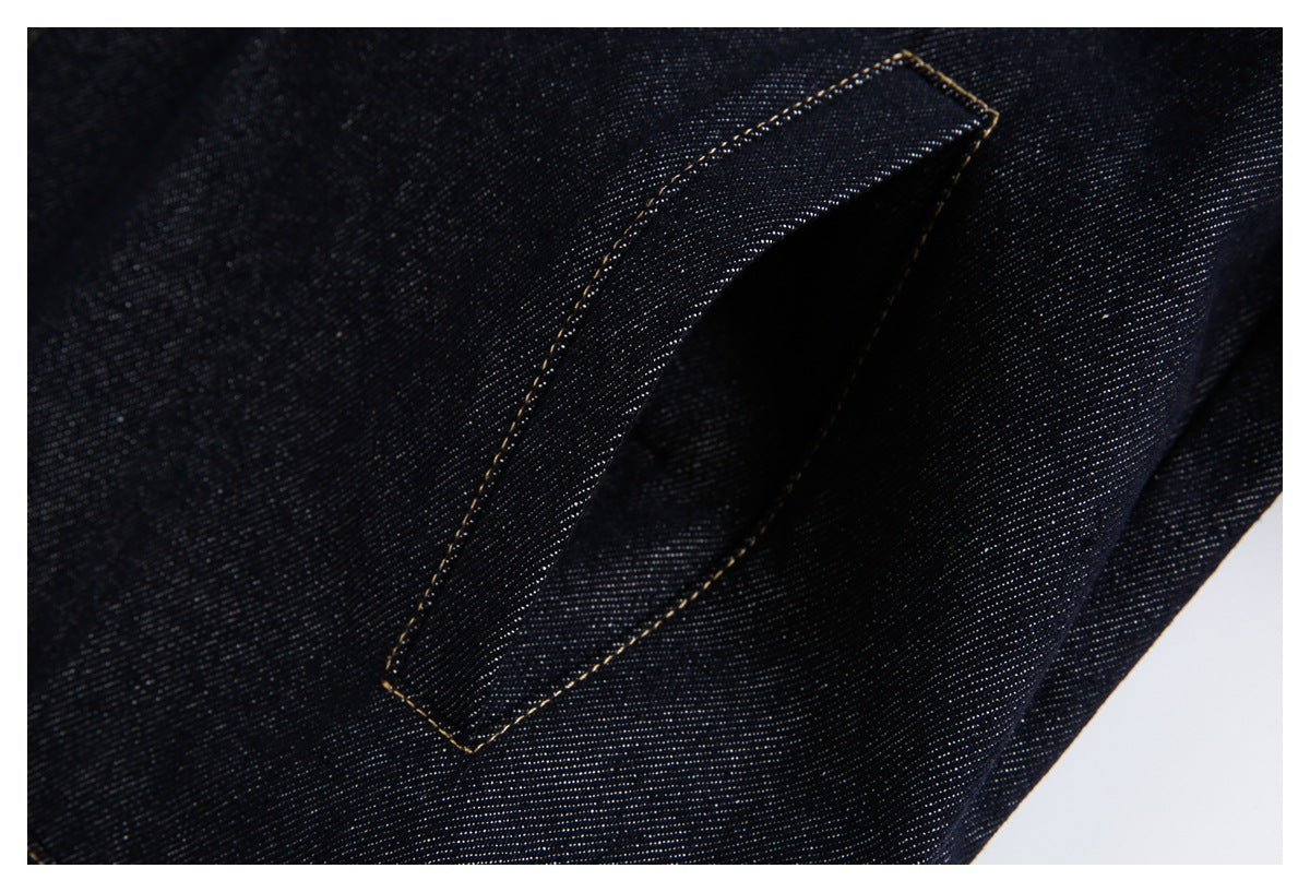 Close-up of a narrow pocket opening stitched into dark indigo denim with tan thread.