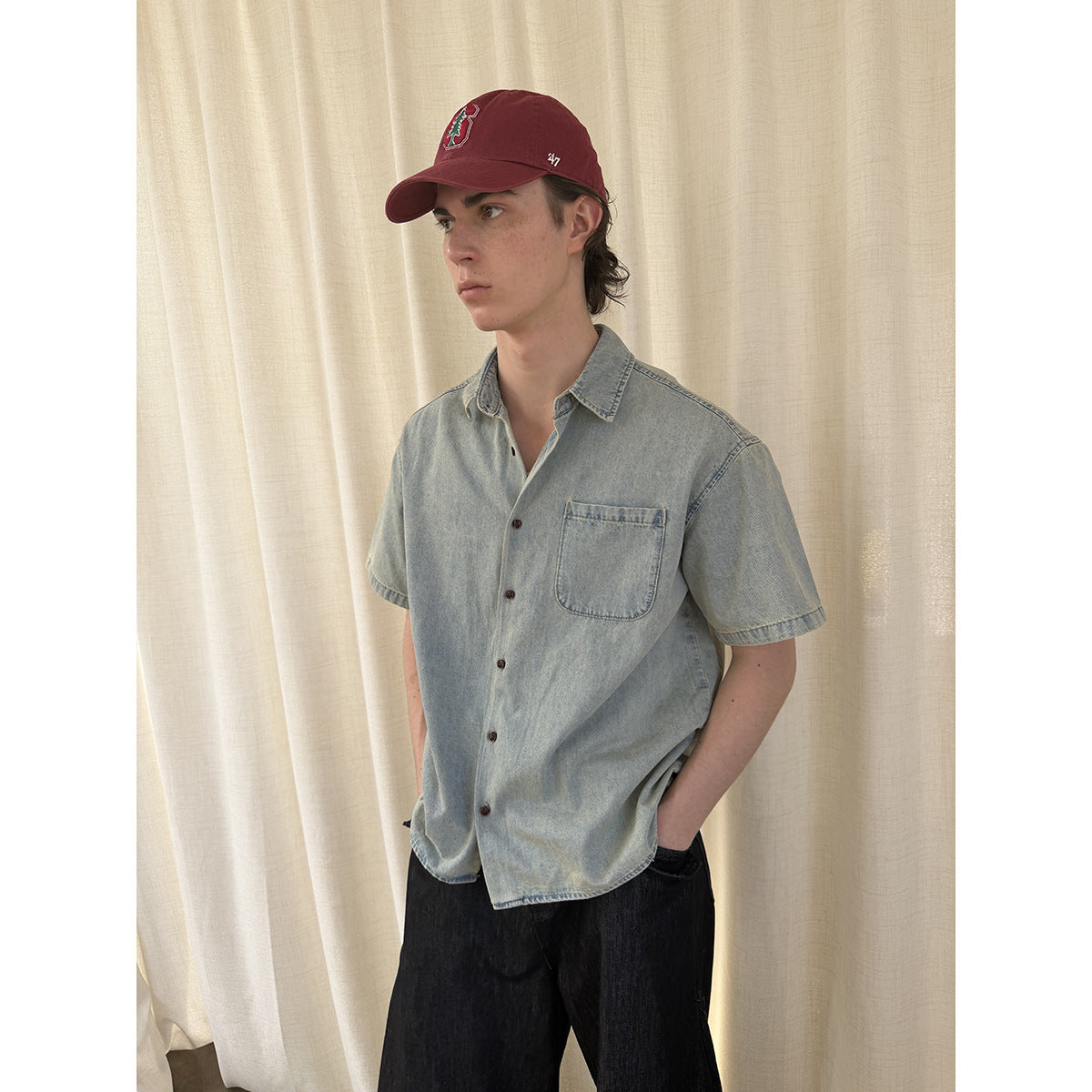 Three-quarter view of a model wearing a light blue short-sleeve button-up shirt with a chest pocket.