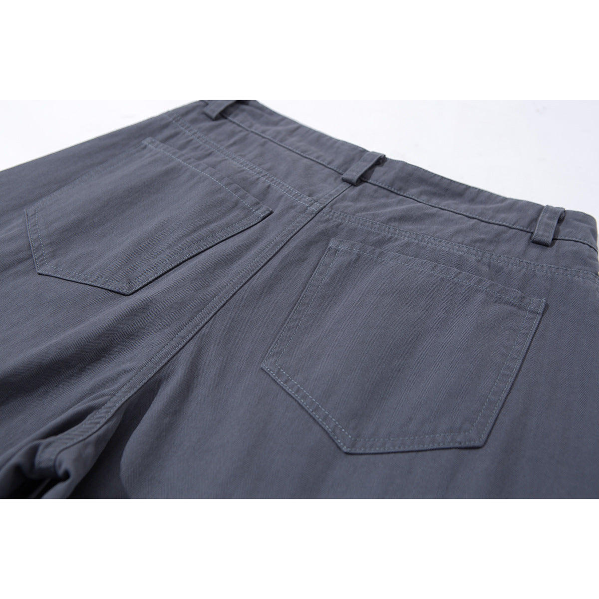 Close-up of charcoal gray trousers from the back, showing two patch pockets, belt loops, and waistband stitching.