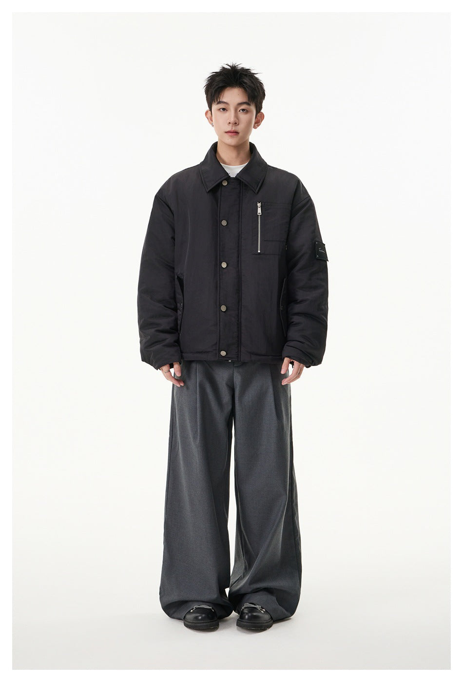 Full-length model wearing black padded collared jacket with wide-leg gray trousers and black shoes