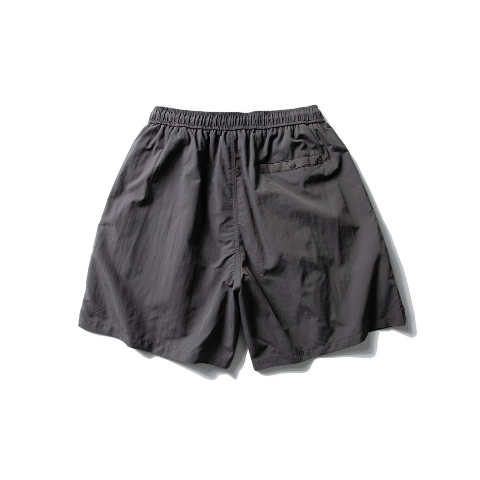 Back view of dark charcoal shorts with an elastic waistband and a single buttoned rear pocket.