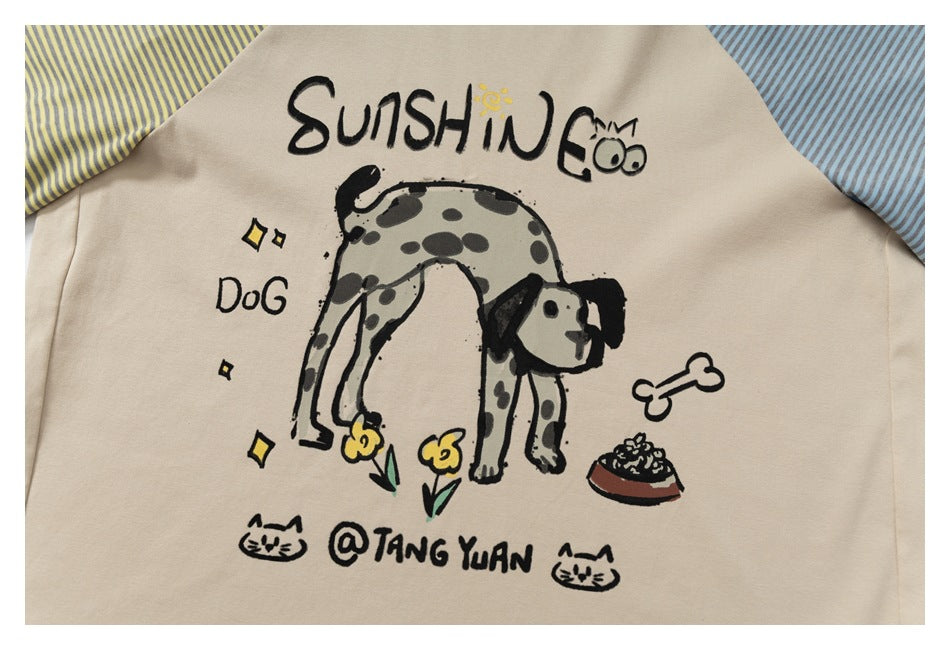 Close-up of a beige garment with a playful dog illustration, English lettering, and striped fabric at the edges.