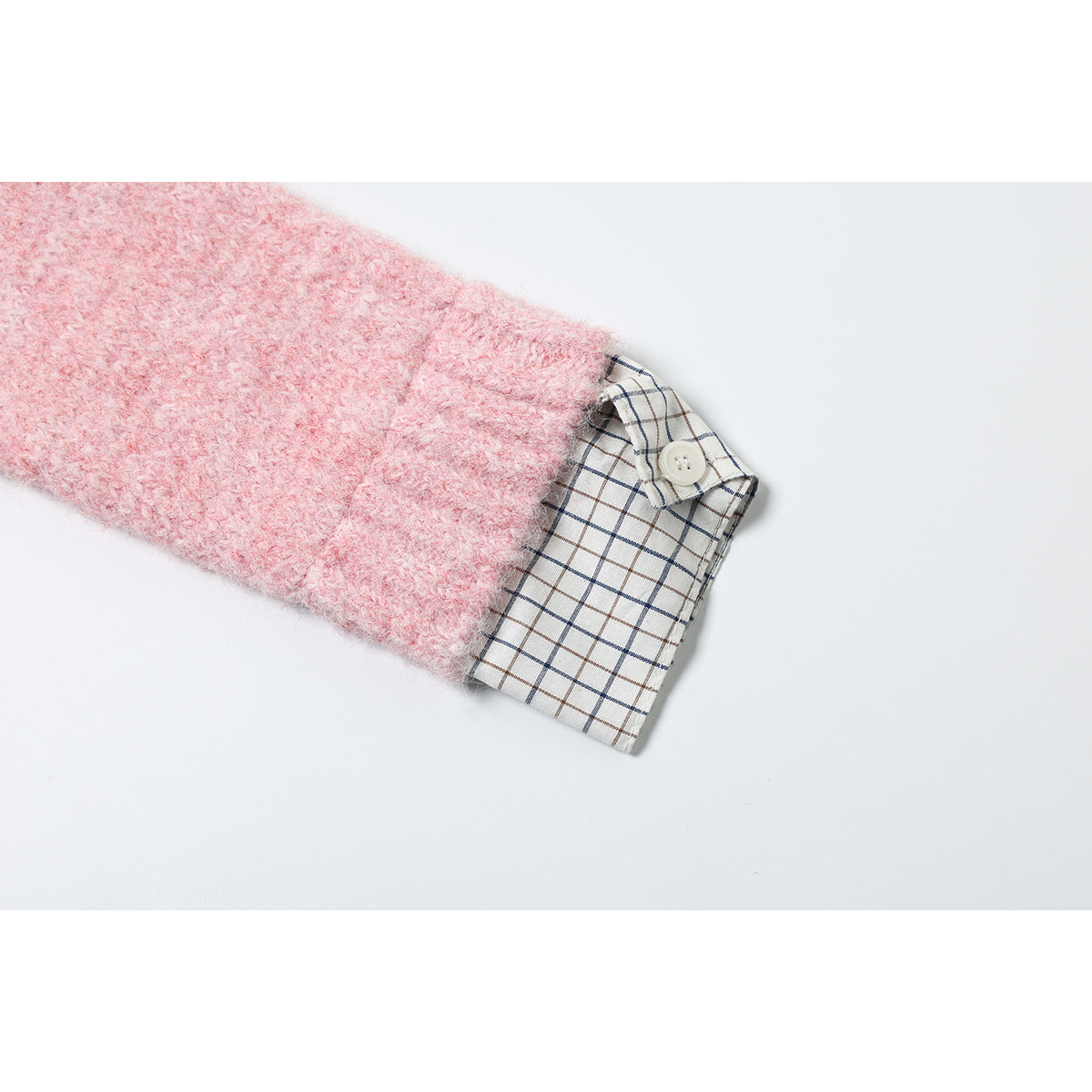 Pink fuzzy knit sleeve cuff folded back to reveal white plaid fabric and a small button.