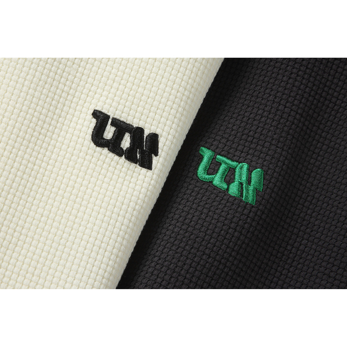Close-up of embroidered logos on ivory and black textured jacket fabric; the black jacket has green embroidery.