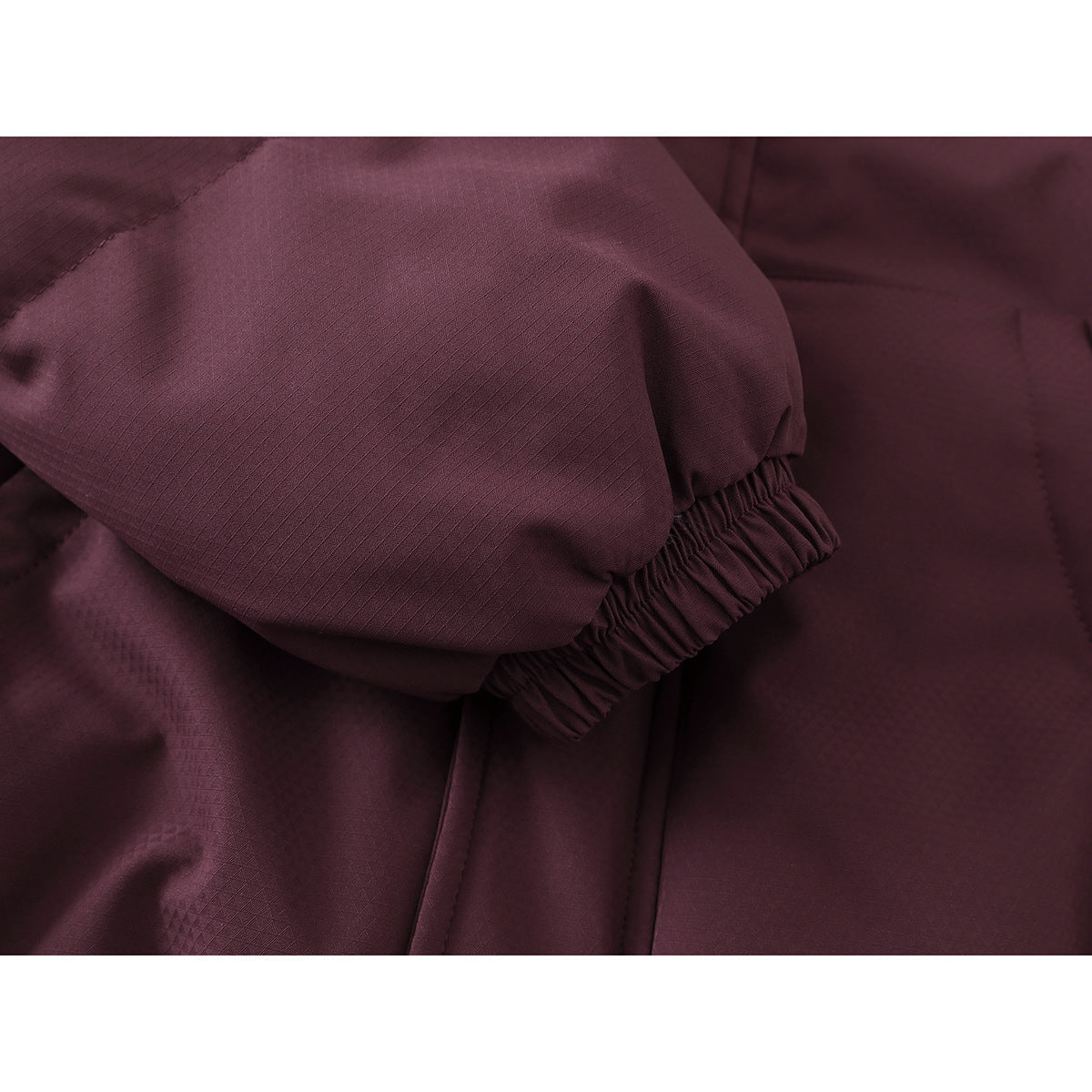 Close-up of a burgundy jacket sleeve with an elastic cuff and subtle textured fabric.
