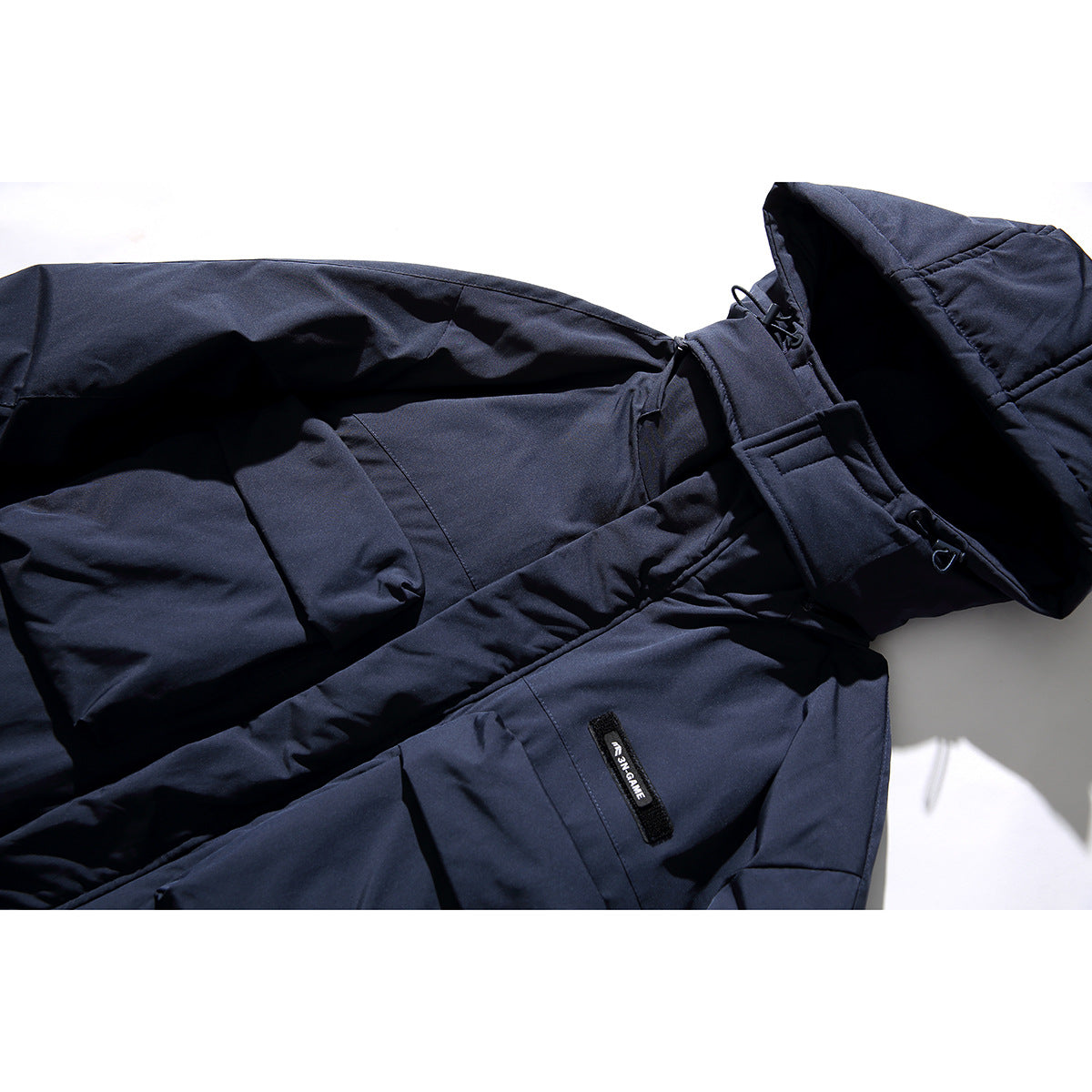 Close-up of a dark navy coat showing its hood, adjustable straps and a small sewn label.