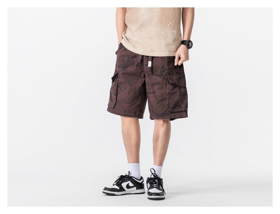 Front view of a model wearing burgundy camouflage cargo shorts with a drawstring waist and large side pockets.