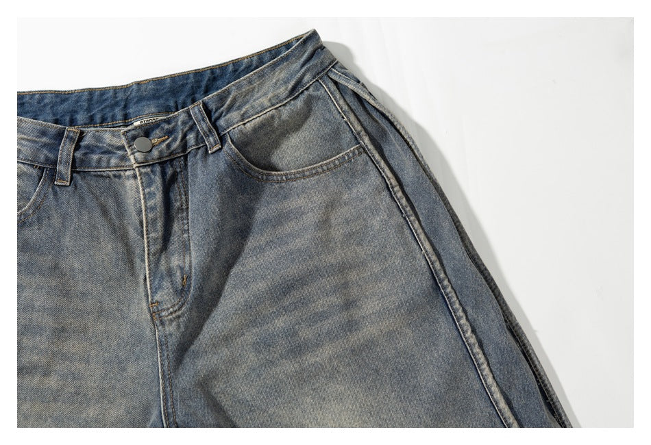 Close-up of the front button, curved pocket and wide side seam on washed gray-blue denim shorts.