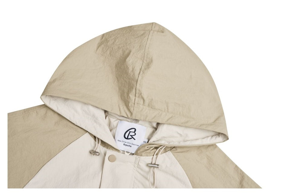 Close-up of the beige hood, drawcords and neck label on a cream pullover jacket.