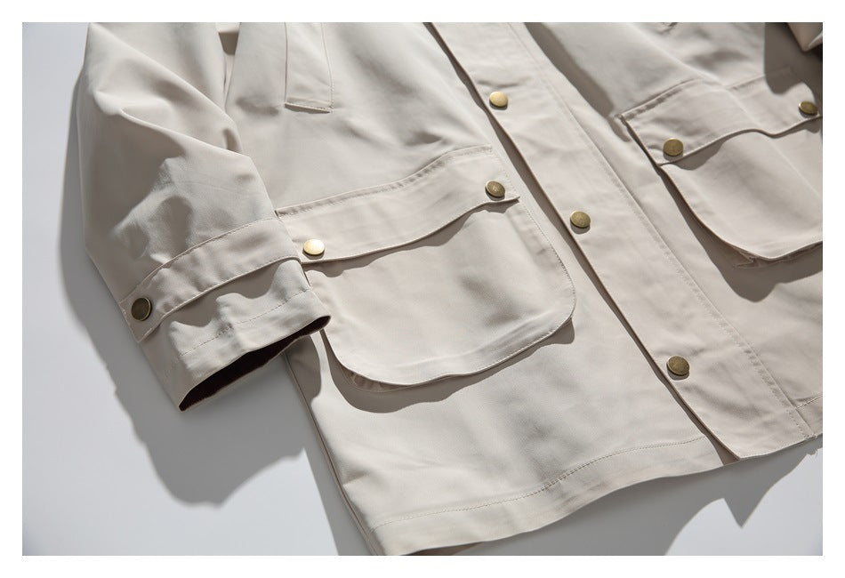 Close-up of a jacket sleeve cuff tab, large flap pocket and brass-tone buttons.