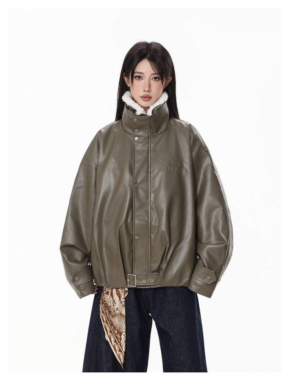 Model wearing the dark green jacket zipped up with the stand collar, hem belt and snap cuffs, with jeans