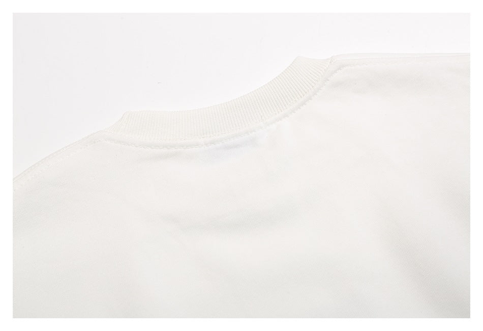 Close-up of a white crewneck garment showing its ribbed collar and shoulder seams.