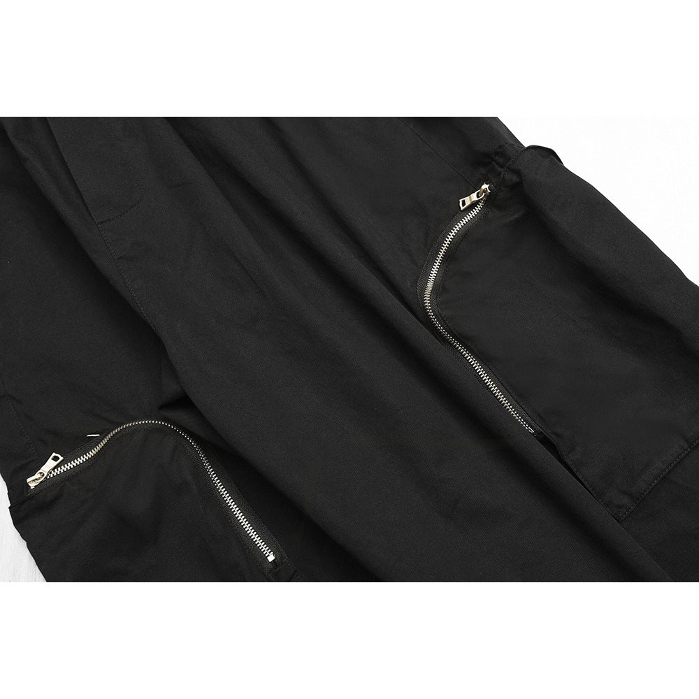 Close-up of black pants with two curved silver-zipper pockets.
