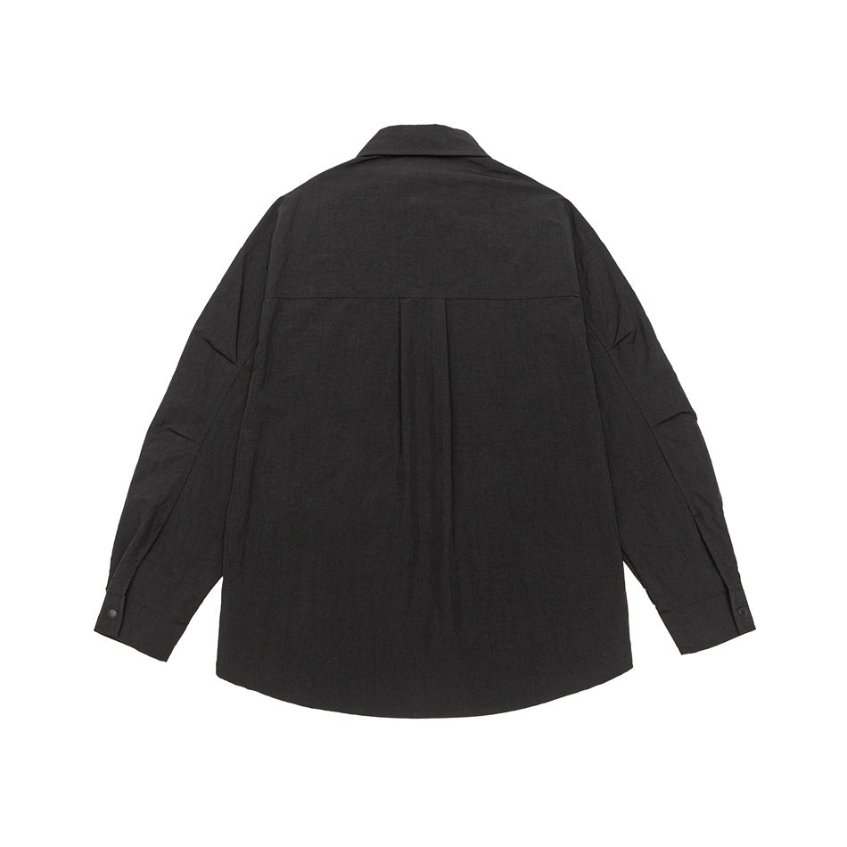 Back view of a black long-sleeve collared shirt with a center pleat and buttoned cuffs.