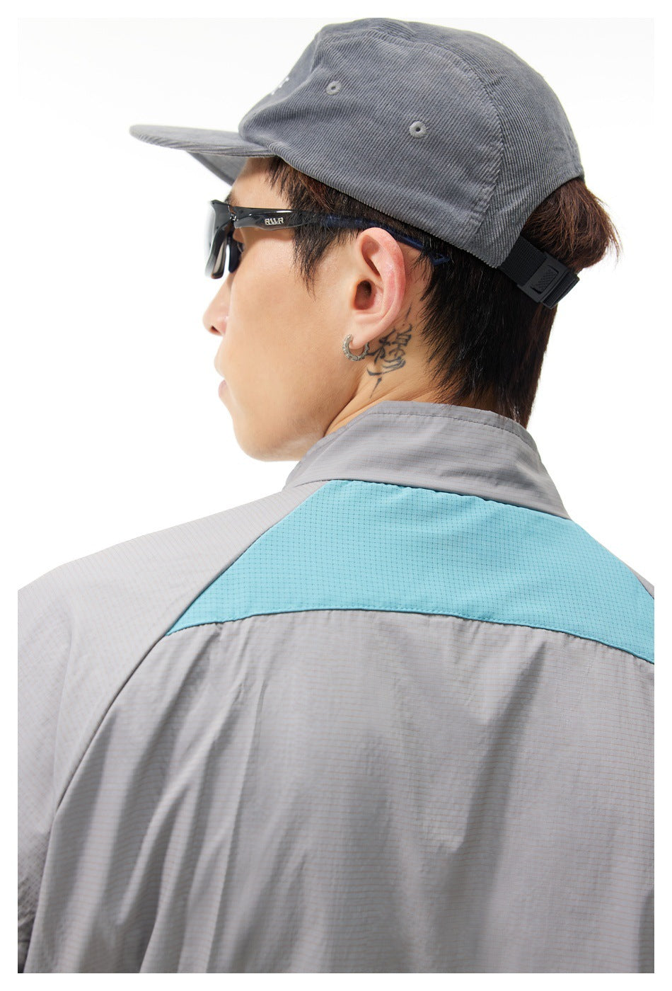Close-up of the jacket's turquoise back yoke and gray collar, with the wearer in profile.