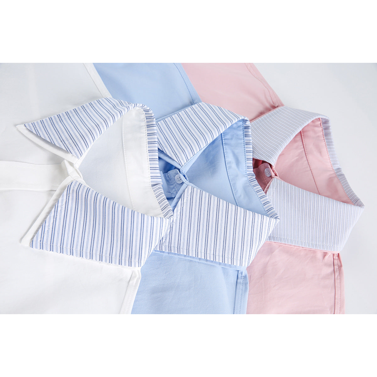 Close view of white, light blue, and pink shirts with blue-striped collars.