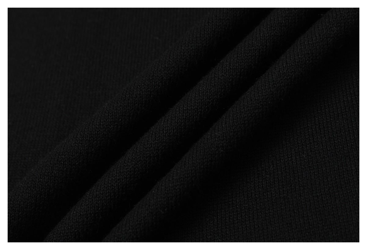 Close-up of black knit fabric draped in folds, showing its fine knit texture.