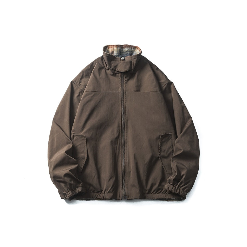 Front flat lay of a dark brown zip jacket with a stand collar, plaid lining, slanted pockets, and elastic cuffs.