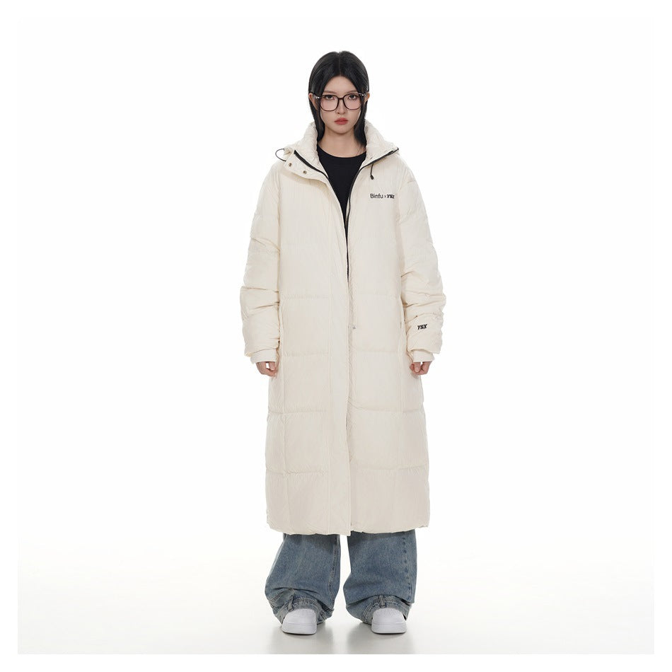 Front view of a model wearing a long ivory hooded puffer coat over a black top and blue jeans.