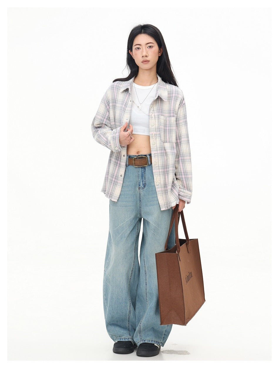 Model wearing an open muted pastel plaid shirt over a white crop top with wide-leg blue jeans.
