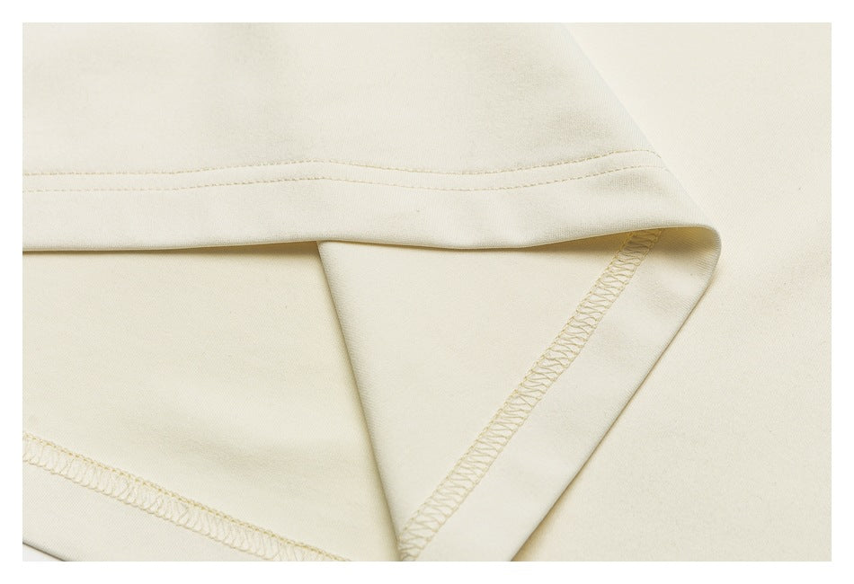 Close-up of an ivory garment hem with parallel stitching and an overlocked seam.