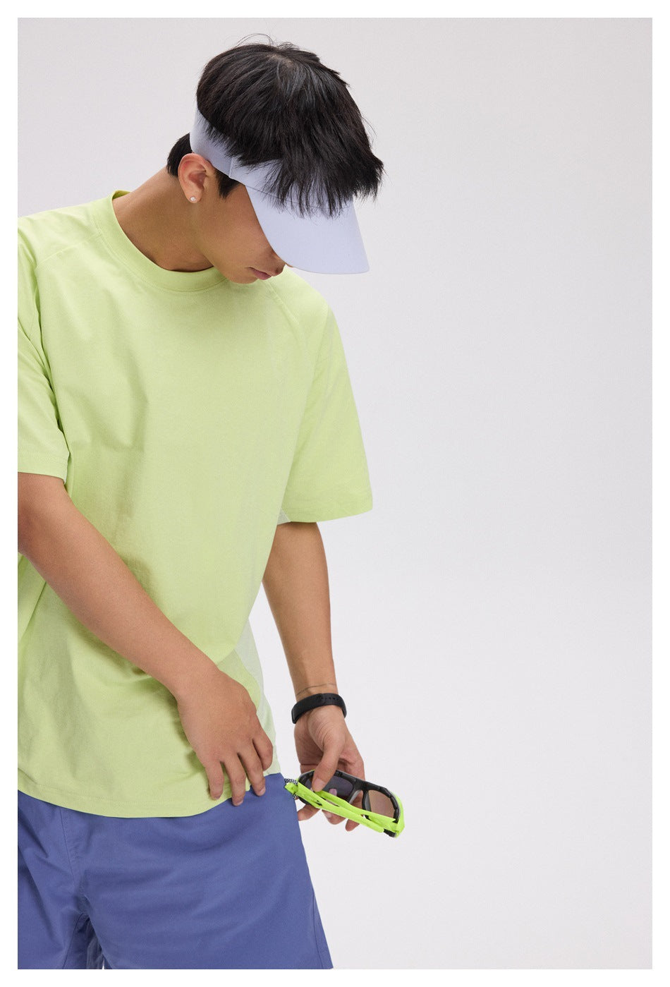 Side view of a model in a pale lime short-sleeve T-shirt and blue-purple shorts.