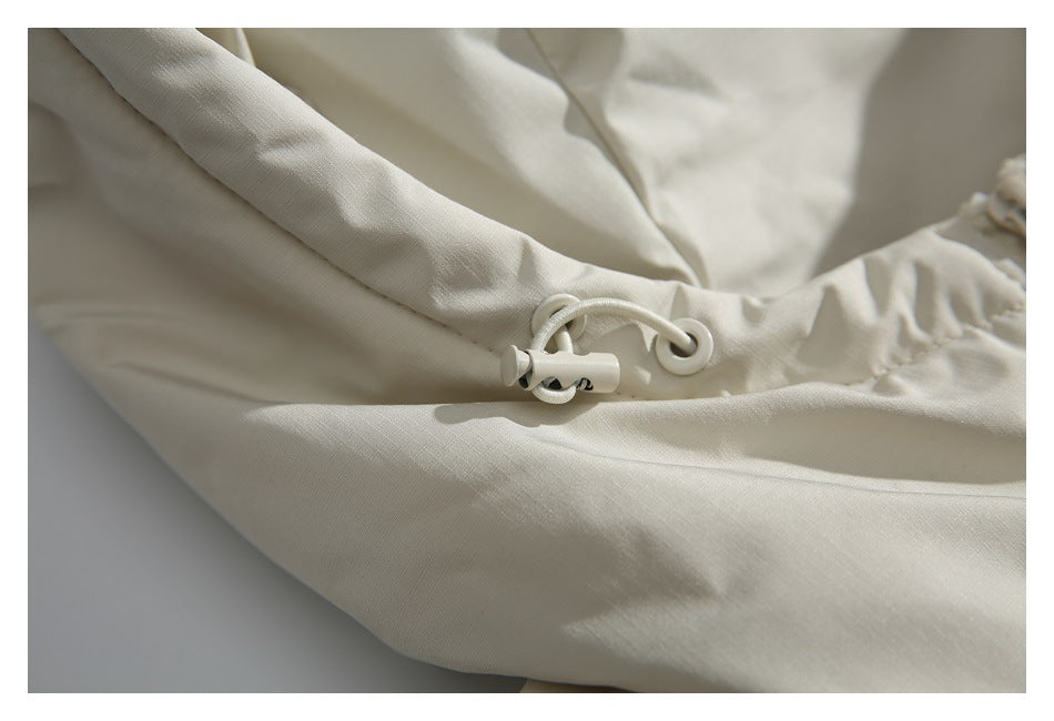 Close-up of an off-white jacket's adjustable drawcord and toggle.